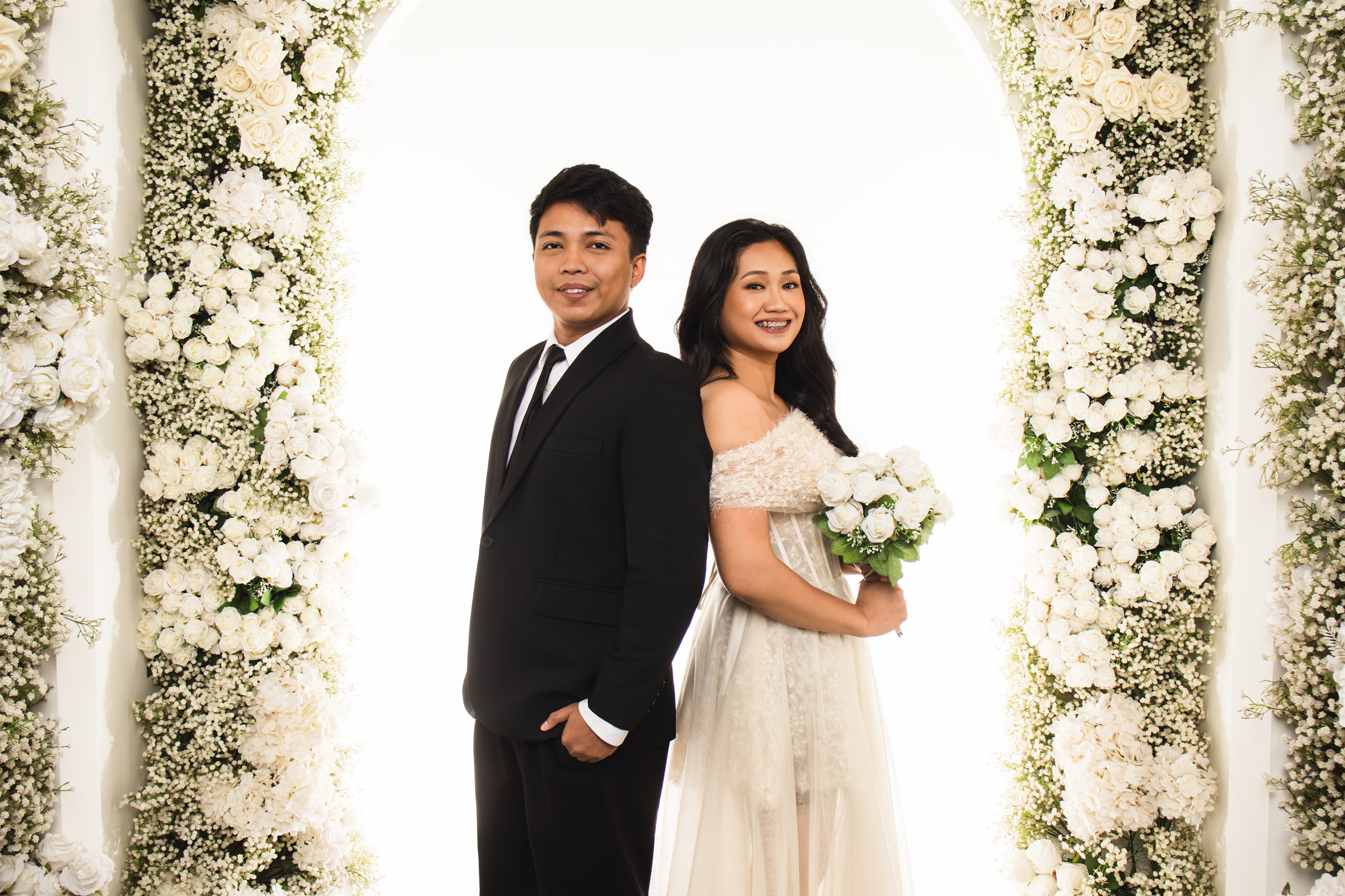 Samuel and Patricia beneath a white floral arch